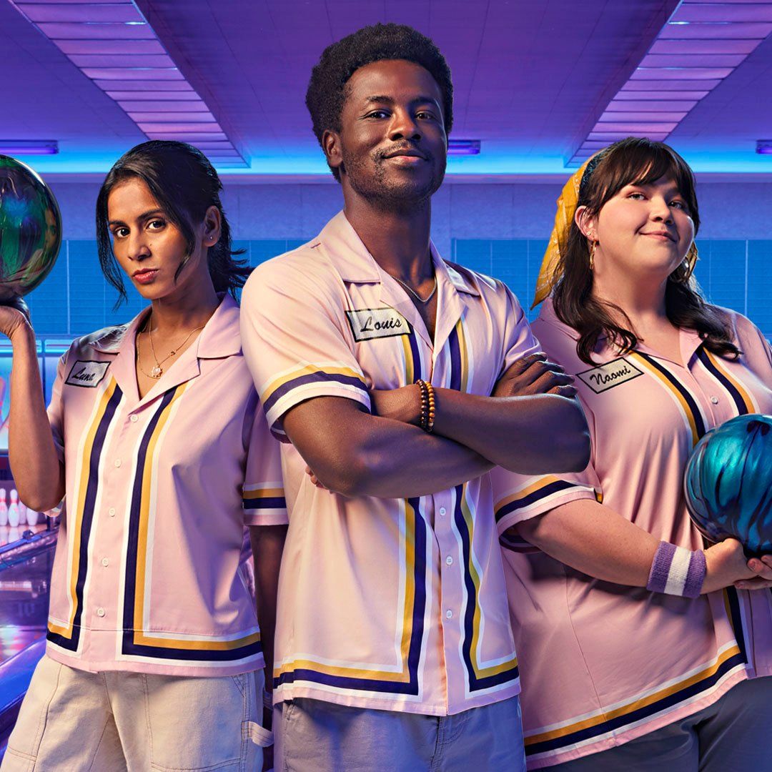 An image of three people on a bowling team posing at the bowling alley.