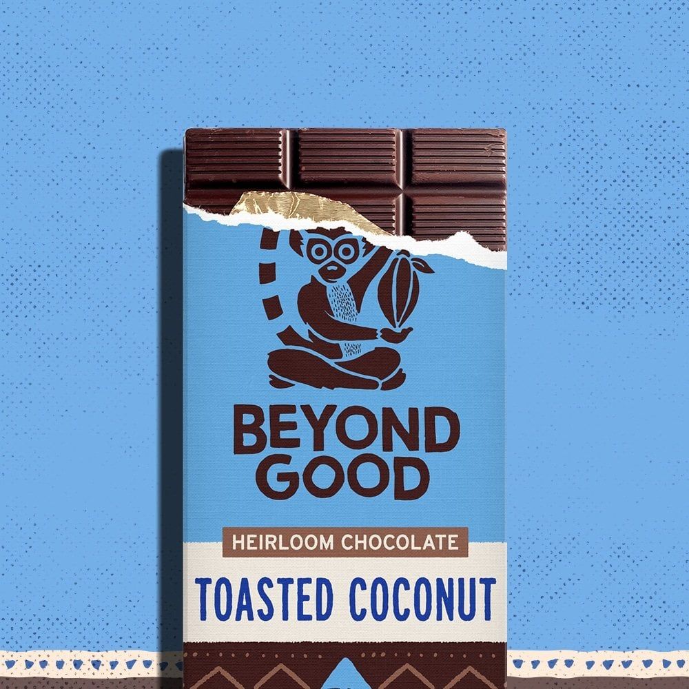 A bar of Beyond Good "Toasted Coconut" chocolate appears on a blue background.
