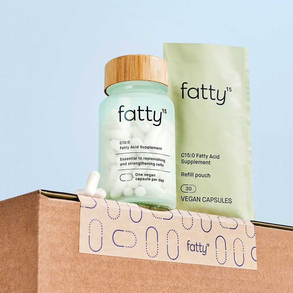 Image of a cardboard box with two products on top: a glass jar and a refill pouch of fatty15, a nutritional supplement.