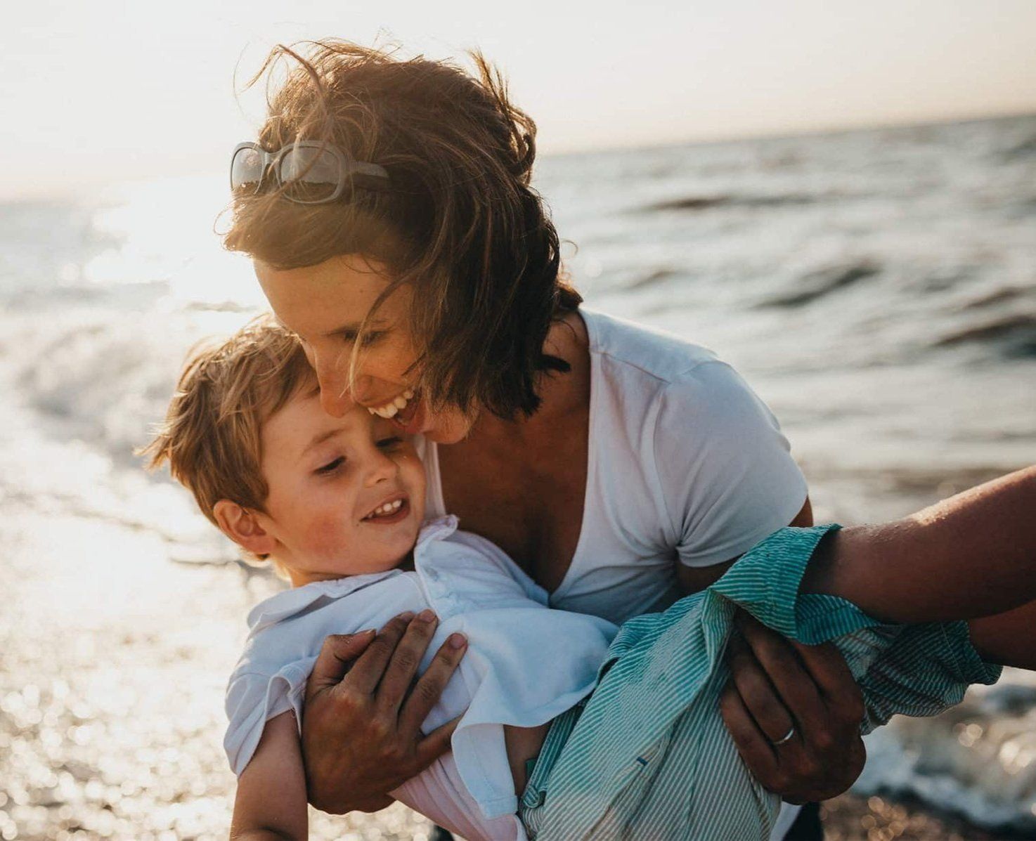 An image of a woman holding a child in front of the ocean An image of a woman holding a child in front of the ocean